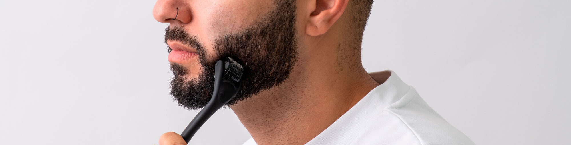 Close-up image of a man with a long beard using a DermTech Derma Roller, showcasing effective beard care and hair growth stimulation for optimal grooming results.