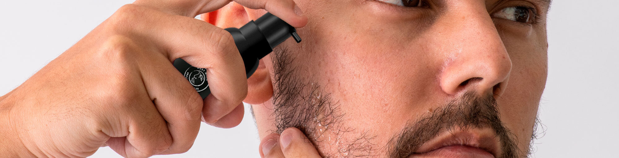 Close-up image of a man with stubble applying DermTech Beard Serum to his face, highlighting effective beard nourishment and growth for optimal grooming results.