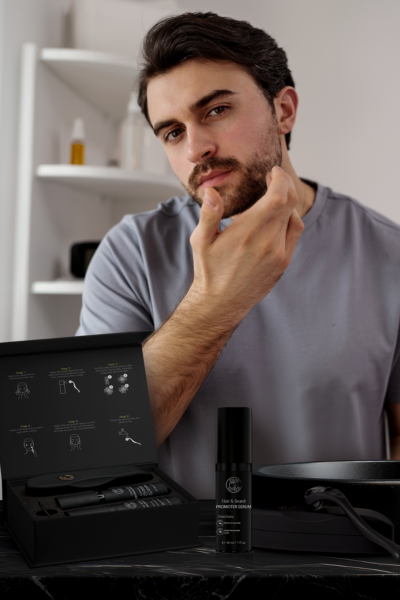 Image of a man showcasing his growing beard while displaying the DermTech kit, highlighting the effectiveness of DermTech products for beard growth and grooming.