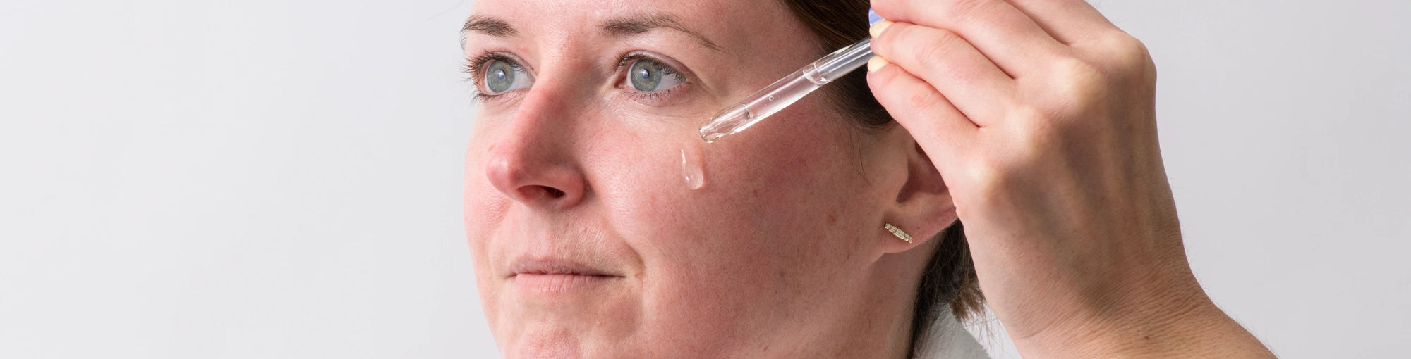 Woman applying hydrating serum or moisturizer to her face after using a derma roller to enhance absorption and skin rejuvenation. Discover the benefits of post-microneedling skincare routines with DermTechRoller.